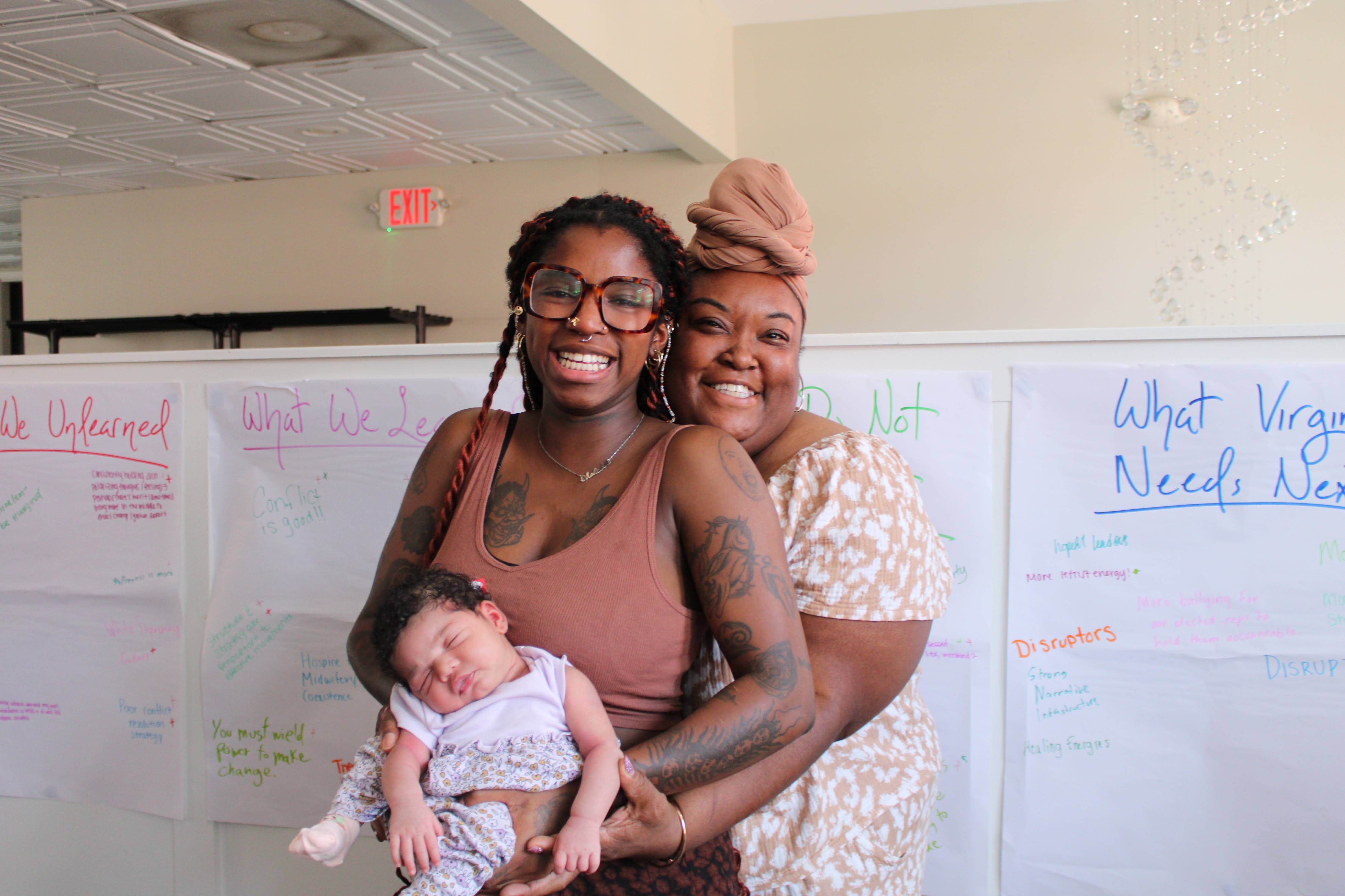 Chantel standing with a mother and baby in a community learning space